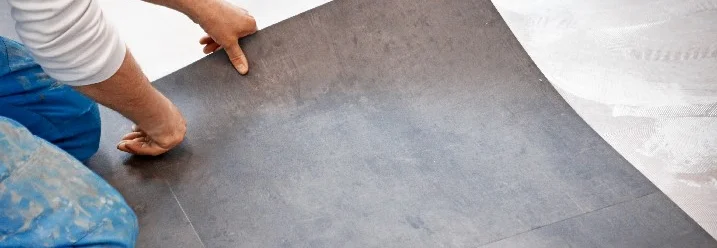 Person verlegt graue Bodenfliese